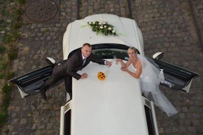 Bruidspaar proost bij een witte limousine